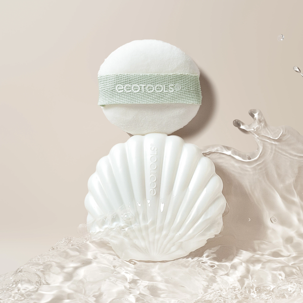 White pearl makeup puff with mint band resting in scalloped shell case with mirror