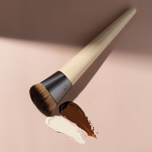 Foundation brush showing beige handle and brown bristles with product smear