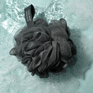 Charcoal bath sponge pouf soaking in water, dark gray mesh puff with ribbon