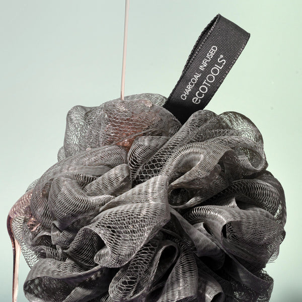 Charcoal bath sponge pouf hanging by a loop, dark gray mesh puff