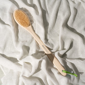 Bath brush with oval natural bristle head on a light cloth, bamboo handle with ecotools.