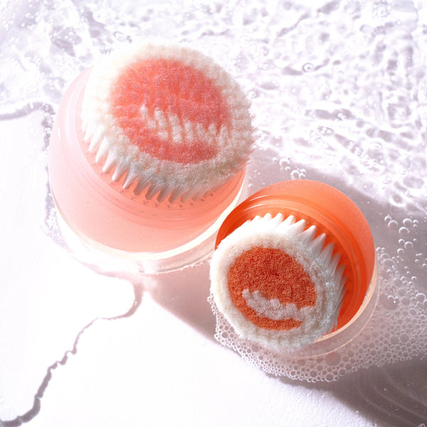 Orange bristle brush head with pink cap showing foam for facial cleansing