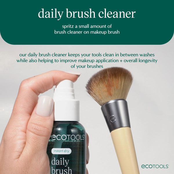 Hand holding brush cleaner spray bottle next to a makeup brush with soft bristles.