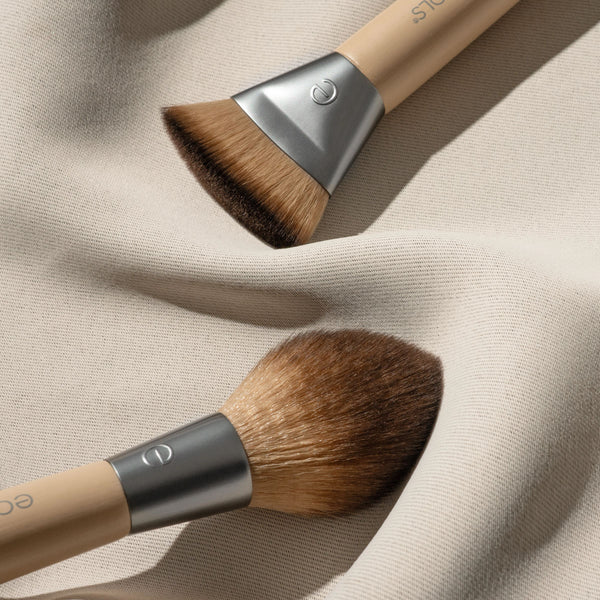 Dual-ended makeup brush on beige cloth, brown bristles and silver ferrules
