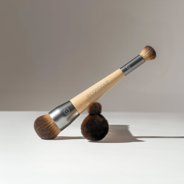 Dual-ended makeup brush lying down with two brown bristle ends