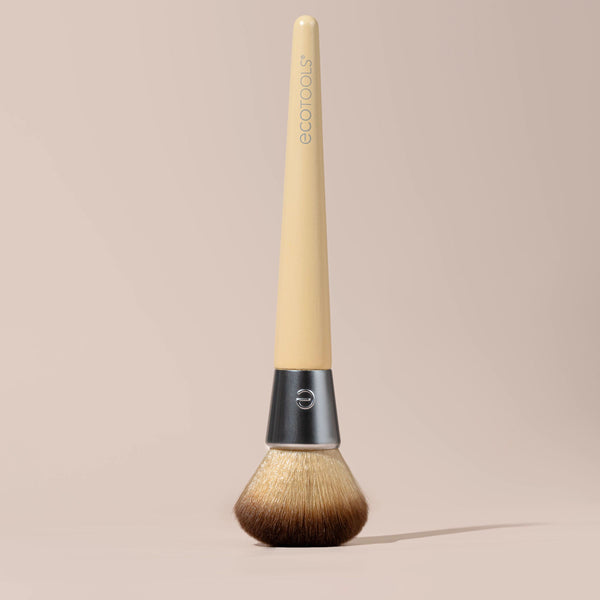 Blending face brush lying down with rounded brown bristles and light beige handle