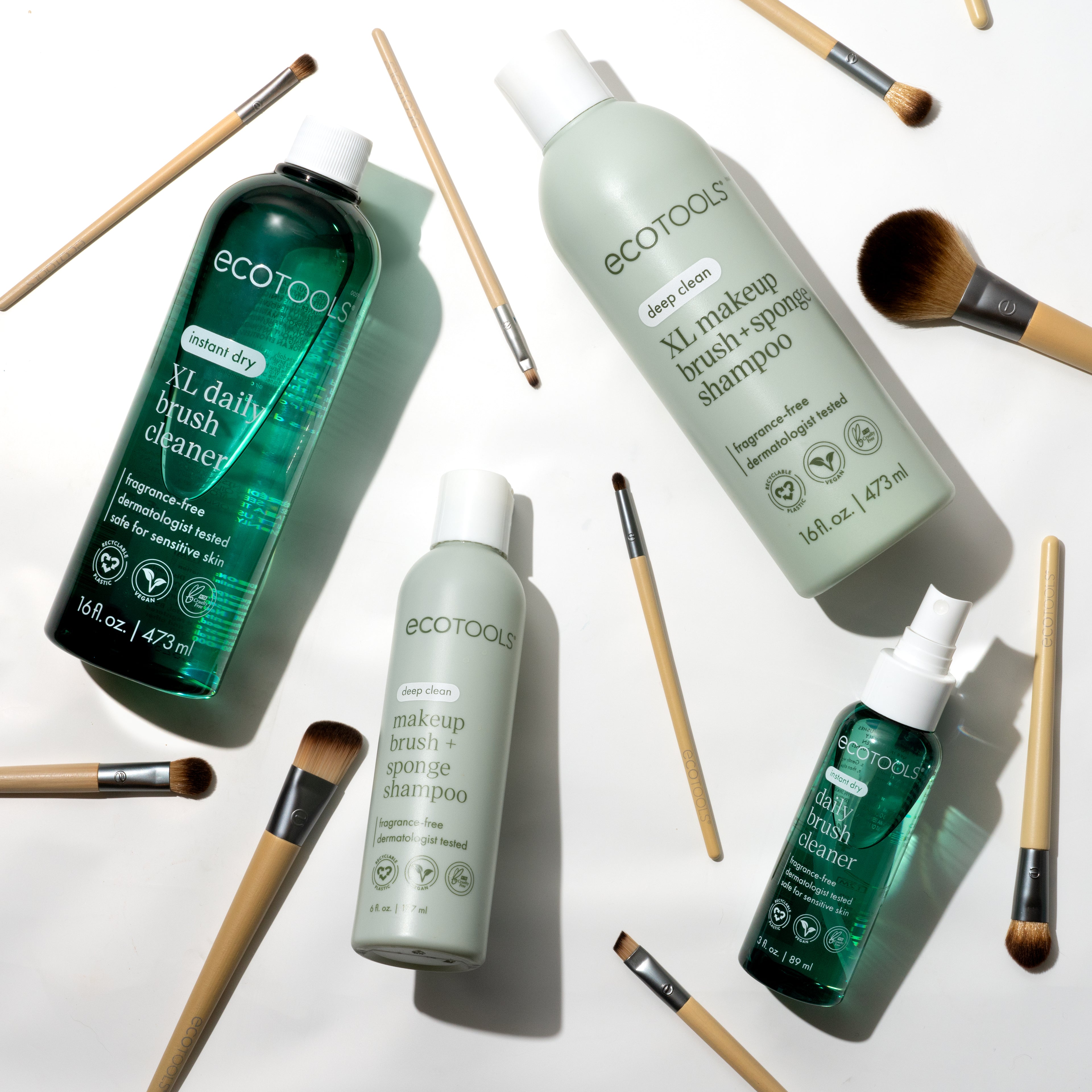 Cosmetic bottles and makeup brushes on a white surface, with green and mint labels and bristles