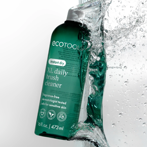 Green XL daily brush cleaner bottle with splashing water droplets beside it.