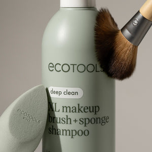 Sage-green shampoo bottle with deep clean label, makeup brush head and sponge nearby