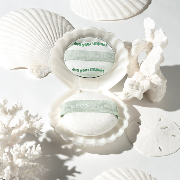 Open scalloped shell case showing mint-banded white puff and round mirror