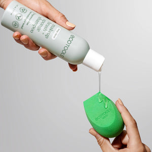 Makeup brush + sponge shampoo bottle dispensing onto green makeup sponge