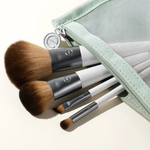 Close-up of 3 makeup brushes with brown bristles and light green zip pouch.