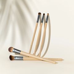 Five beige-handled eye makeup brushes laid out with brown and soft brush heads