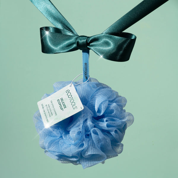 Delicate EcoPouf mesh cleansing puff tied with teal ribbon, light blue