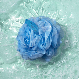 Light blue Delicate EcoPouf mesh cleansing puff floating in soapy water bubbles