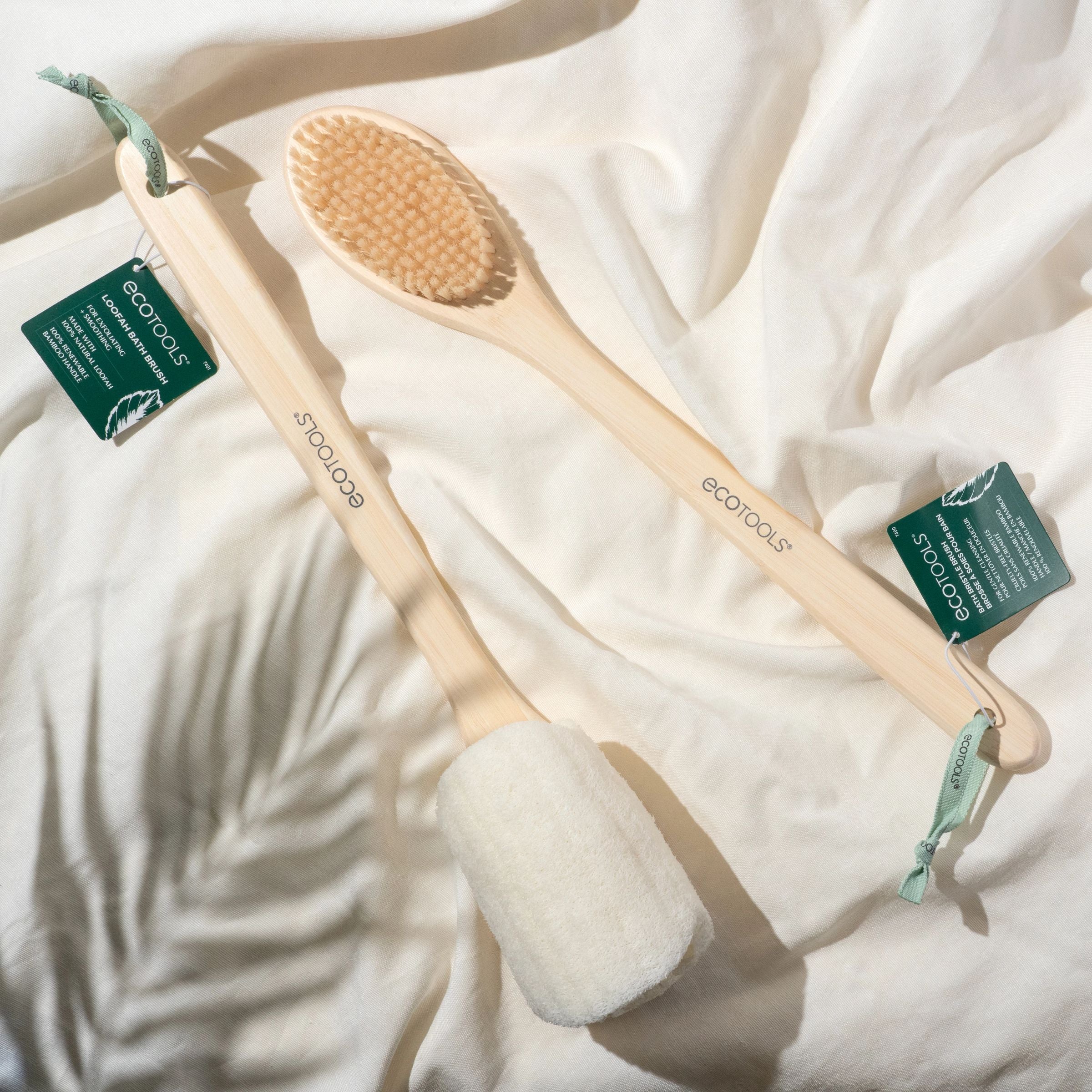 Wooden bath brush with soft bristles and green tags on a white cloth background