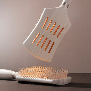 Round-bristle detangling hair brush with light wood handle and heated/orange-tipped pins
