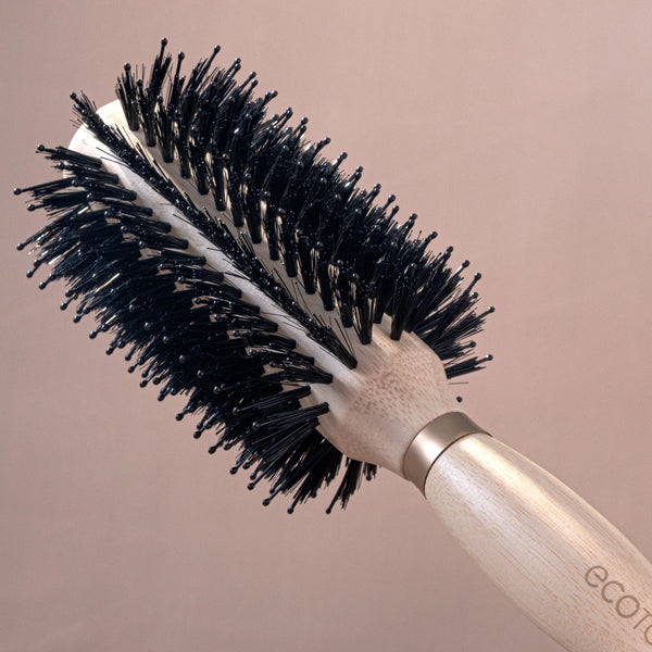 Round hair brush with light wooden handle and thick black bristles for volume styling
