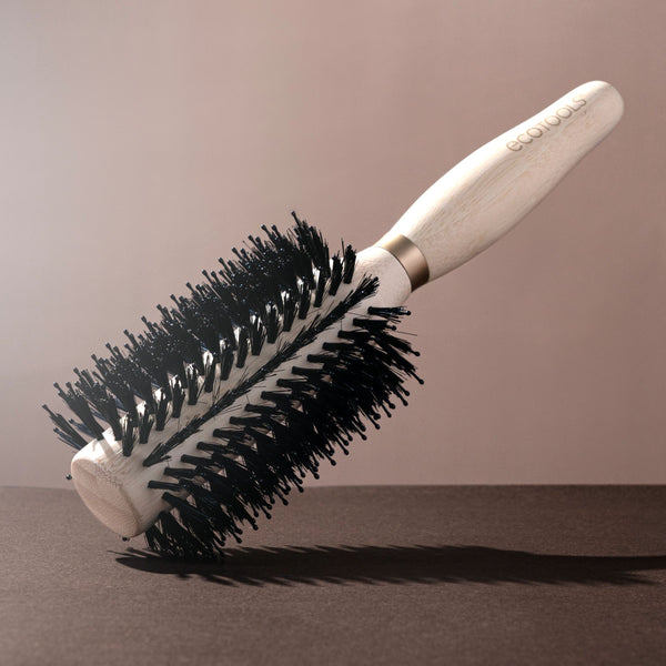 Volumizing round hair brush with light wooden handle and dense black bristles
