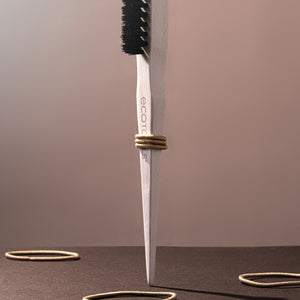 Slick back brush held upright showing cream handle and dense black bristles