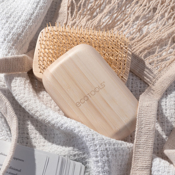 Light tan travel detangling hair brush with dense bamboo bristles and rounded handle