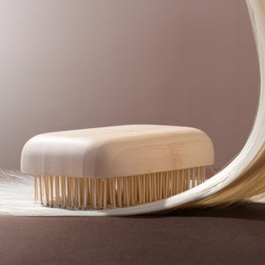 Light tan travel detangling hair brush with bamboo handle and long bristle tips