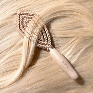 Fine hair detangler brush resting on blonde hair with pin bristles close-up