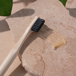 Edge defining brush with dark bristles and light bamboo handle on cleaning stone