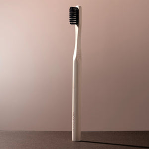 Edge defining brush with light bamboo handle and dark bristle head for styling edges