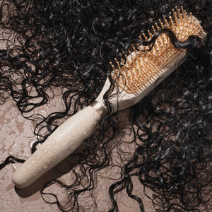 Hair detangling brush used on dark, curly hair