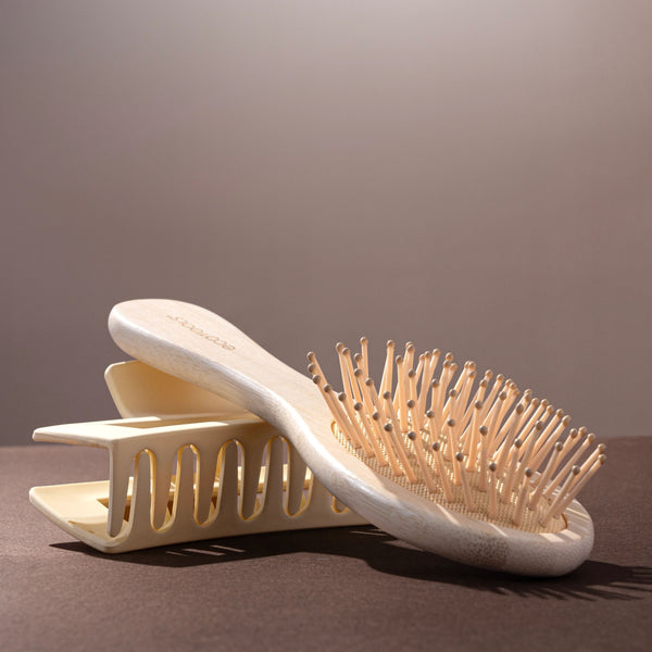 Mini detangler brush with light wooden handle and oval pin brush head