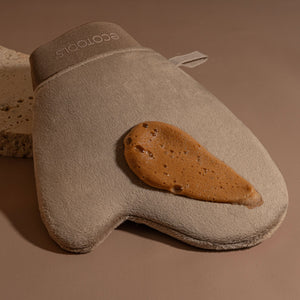Beige tanning mitt holding self-tanner on the application surface