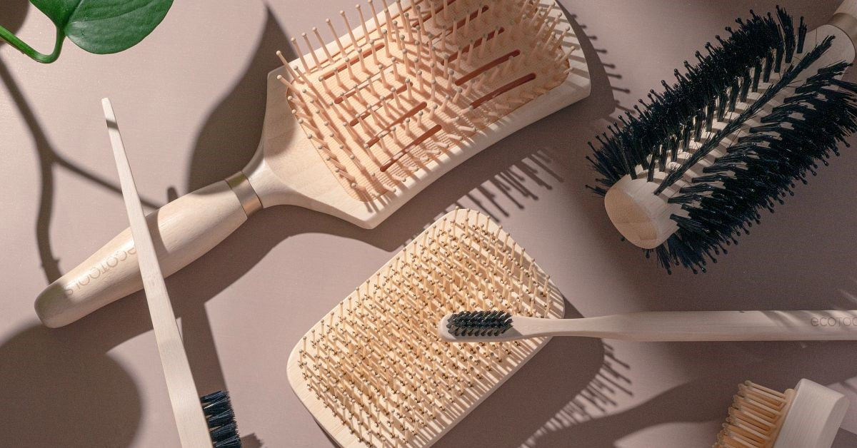 Assorted wooden hairbrushes and black bristle brushes on a light surface with scattered combs