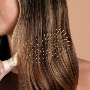 Hair detangling brush brushing long brown hair with pin bristles