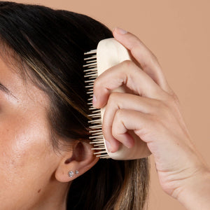 Cushioned paddle hairbrush brushing dark hair with white bristles