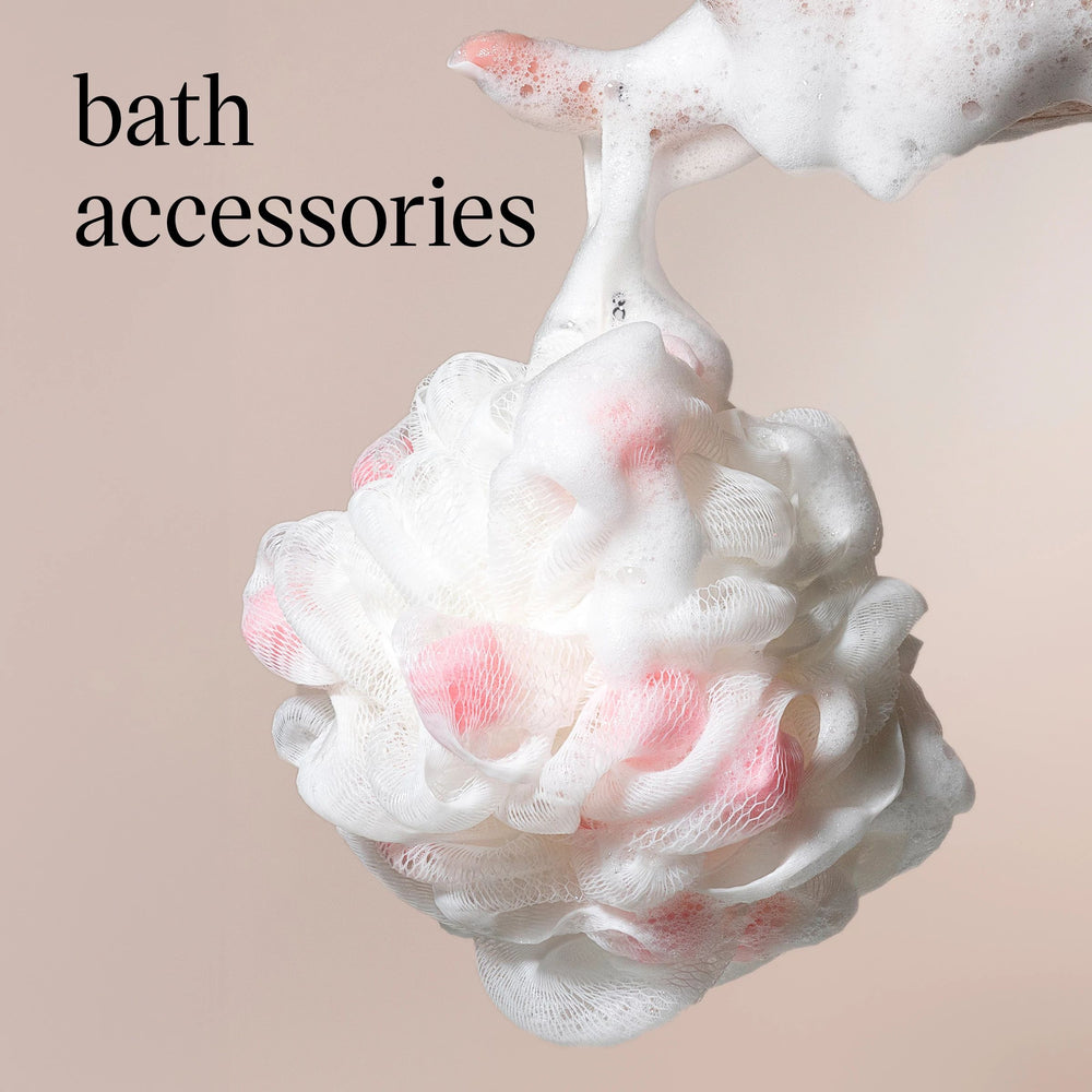 Bath accessories text over a foamy, lathered soap sculpture with pink bubbles on a beige background