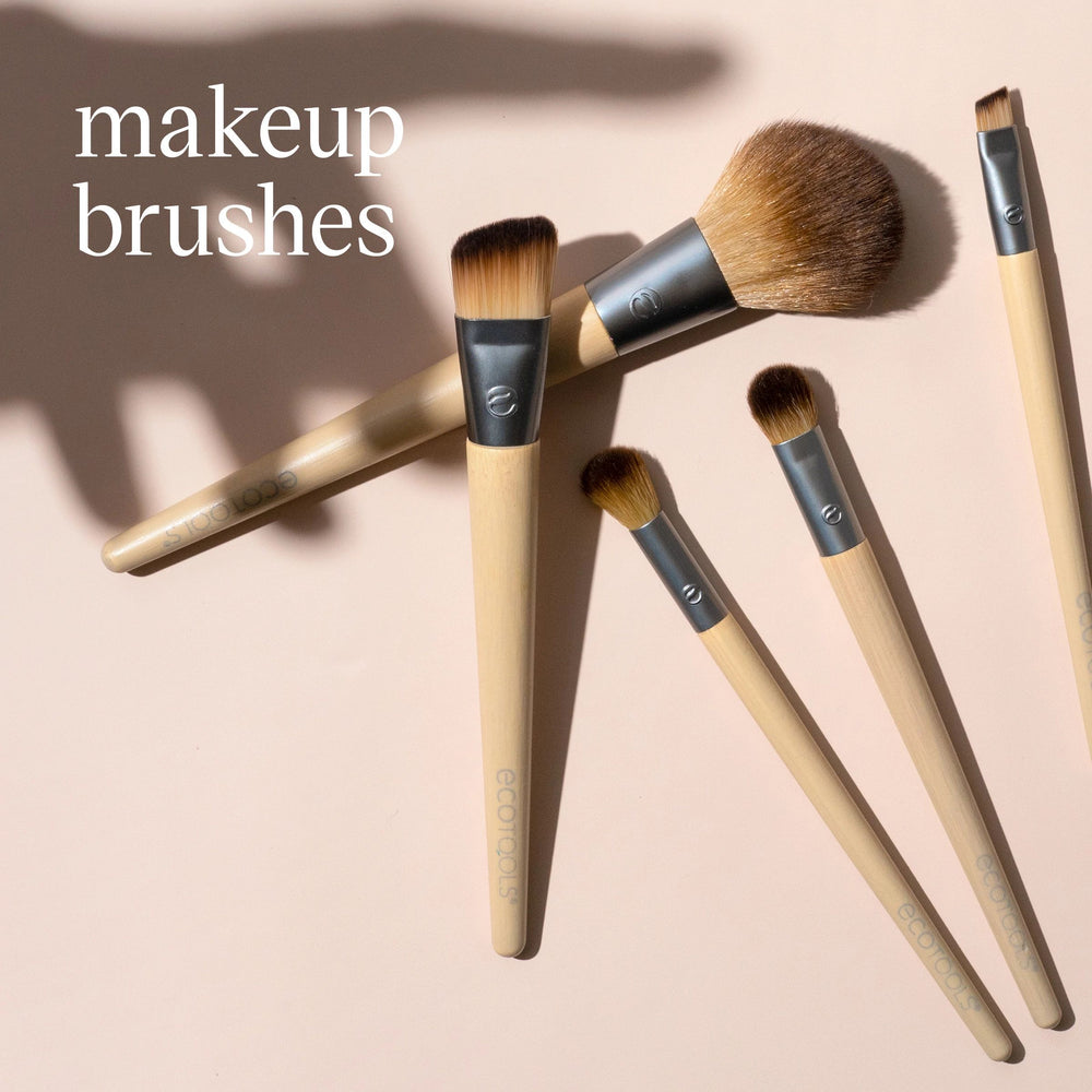 Makeup brushes with soft brown bristles on light pink background, including a flat wide brush and smaller brushes