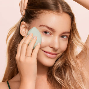 Makeup blurring blender sponge pressed against cheek during application