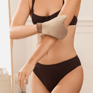 Beige tanning mitt on forearm while applying self-tanner to skin