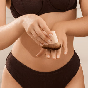 Self-tan blending brush applying product to skin on a person’s legs