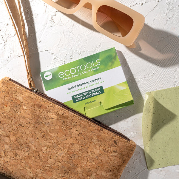 Facial blotting papers box beside a small pouch with pale green sheets