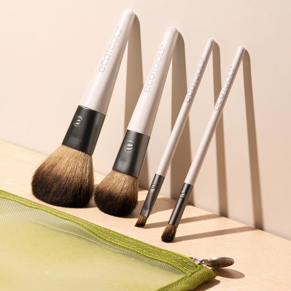 Makeup brush kit with 4 brushes on green pouch; brown bristles, white and dark handles.