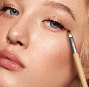 Close-up of eye makeup application using an angled brush with brown bristles