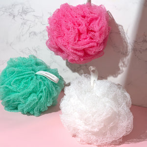 Assorted exfoliating bath sponges in teal, pink, and white with hanging loops