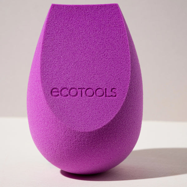 Purple teardrop makeup sponge with visible ecotools logo on textured surface