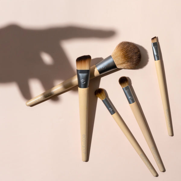 Five makeup brushes with beige handles and silver ferrules, brown bristles arranged