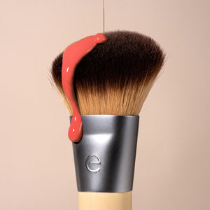 Makeup brush with soft brown bristles and matte silver handle with blush smear