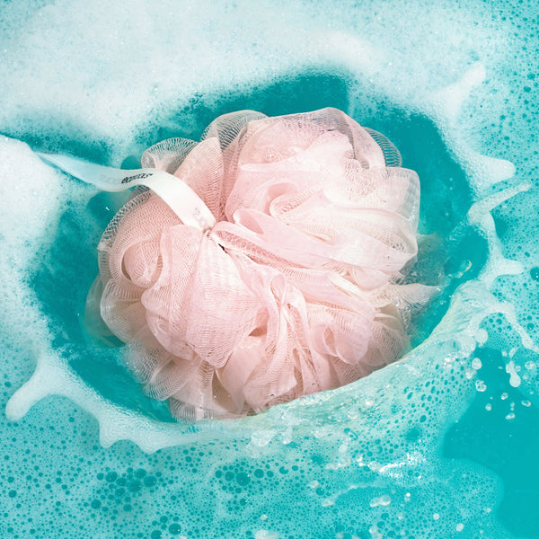 EcoPouf® bath sponge, pale pink ruffled mesh submerged in foamy water