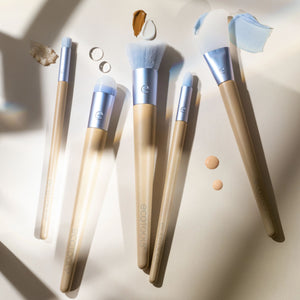 Skincare brush set with five blue-and-cream brushes on a surface with makeup swatches.