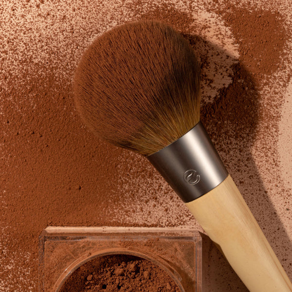 Powder brush with large rounded bristles dusted with brown powder